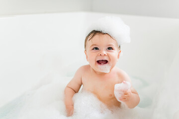 Baby boy bathes in a bath with foam and soap bubbles