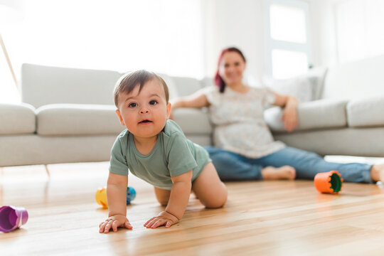 Mother and the Cute 8 month baby laying on floor, playing with toys