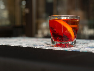 Classic Italian Negroni cocktail on the table, garnish with a slice of fresh orange, made with London Dry gin, Campari, and sweet vermouth