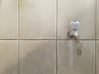 front view of the water faucet against the background of the ceramic wall in the bathroom of the house. home interior background concept, decoration, exterior, building, architecture, construction