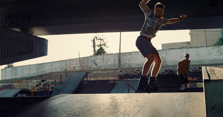 Teenage athletes performing stunt together at city bright sun skate park. 