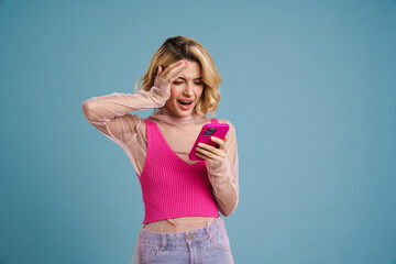 Fototapeta premium Young white woman expressing surprise while using mobile phone