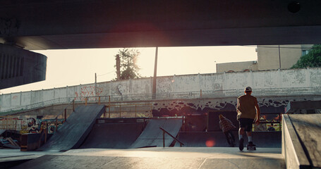 Fototapeta na wymiar Active people riding together at urban skate park. Friends practicing outdoors