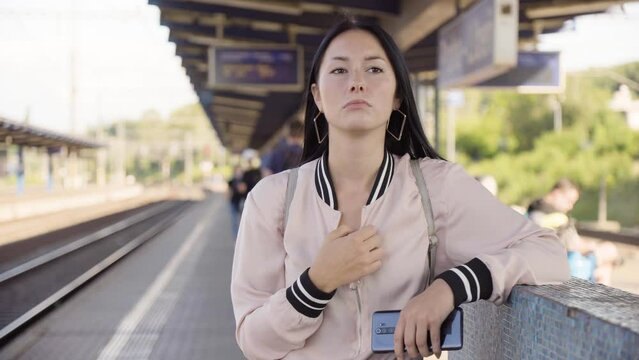 A young beautiful Caucasian woman thinks about something at a train station