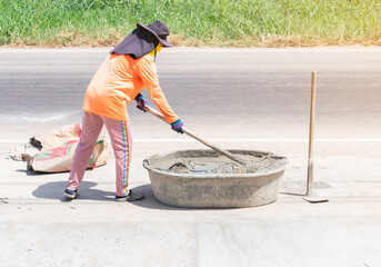 Worker use shovel mix mortar in bucket on road construction.