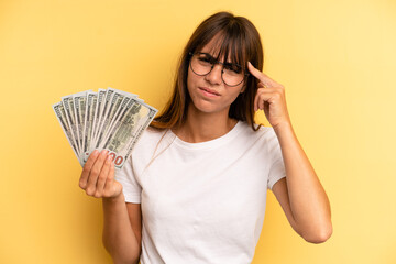hispanic woman feeling confused and puzzled, showing you are insane. dollar banknotes concept