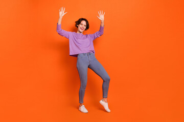 Full length photo of funny adorable girl dressed purple pullover dancing empty space isolated orange color background