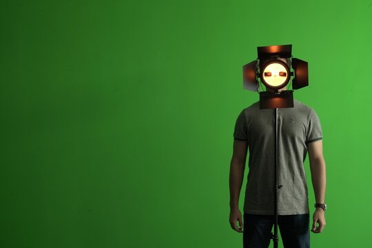 Man standing with a helmet of Game Virtual Machine and a green chroma in the background, copy space