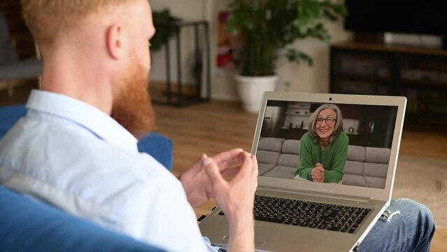 A guy waving hand, greeting with a senior woman on the laptop screen, student talking on virtual meeting with elderly female tutor, an adult son calls to mother via video call. Social distancing