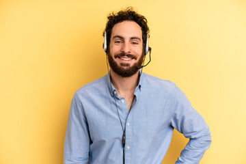 young man smiling happily with a hand on hip and confident. telemarketer concept