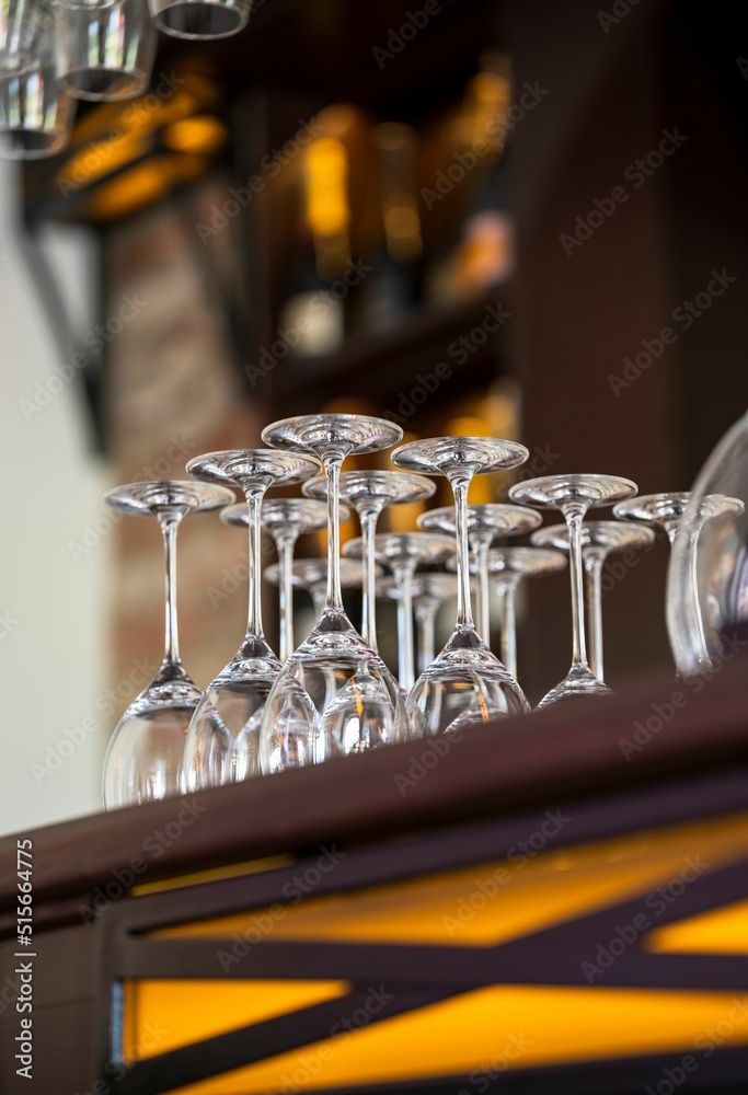 Poster empty wine glasses on a bar rack on a blurred background