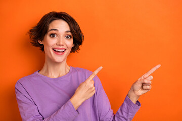Photo of excited cheerful lady indicate fingers empty space proposition isolated on orange color background