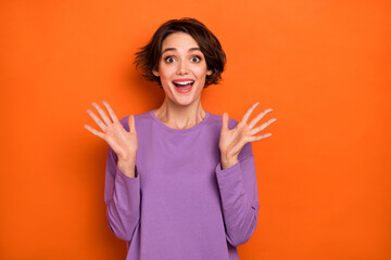 Portrait of impressed cheerful lady raise opened arms palms cant believe isolated on orange color background