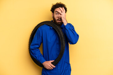 young man looking shocked, scared or terrified, covering face with hand. bike mechanic concept