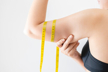 Close-up of a woman grabbing upper arm with excess fat. Pinching the loose and saggy muscles. Woman...
