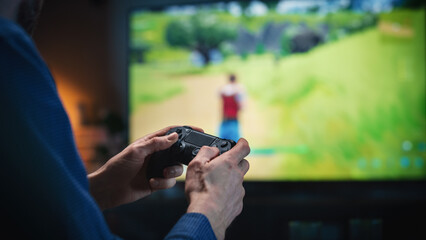 Close Up on Man's Hands at Home, Sitting on a Couch in Stylish Loft Apartment and Playing Arcade Shooter Video Game on Console. Male Using Controller to Play MMO Battle Royale Style Game Online.