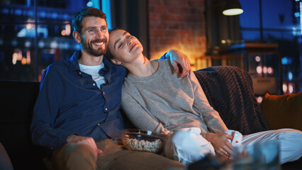 Portrait of Beautiful Couple Spending Time at Home, Sitting on a Couch, Hugging and Watching...