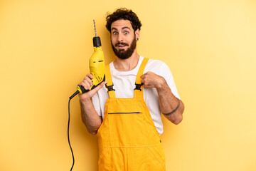 young man feeling happy and pointing to self with an excited. handyman with a drill