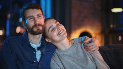 Portrait of Beautiful Couple Spending Time at Home, Sitting on a Couch, Hugging and Watching...