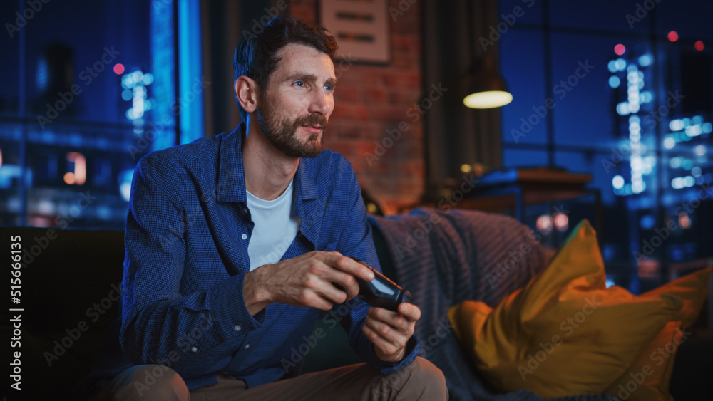 Wall mural portrait of young handsome man spending time at home, sitting on couch in stylish loft apartment and