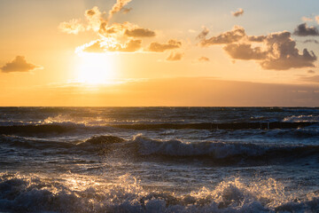 Obraz premium colored sunset with cloud cover over the sunset at the beach - dramatic sunset on the baltic sea
