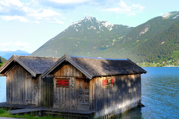 wooden hangar on water, boathouse for boats and boats on stilts, surface of mountain lake Achensee...