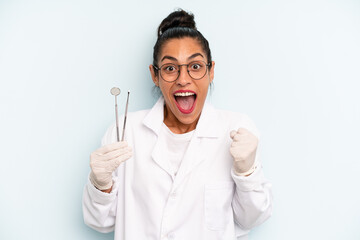 hispanic woman feeling shocked,laughing and celebrating success. dentist concept