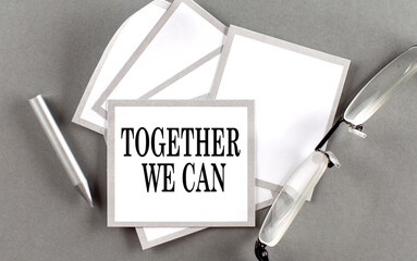 TOGETHER WE CAN text written on a sticky with pencil and glasses