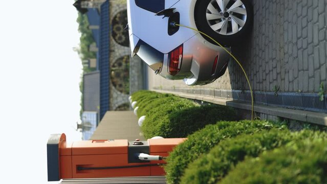 Vertical format video of electric vehicle parking at the charging station. Electric vehicle battery cell recharging. Zero emission vehicle on EV only charging station is parked.