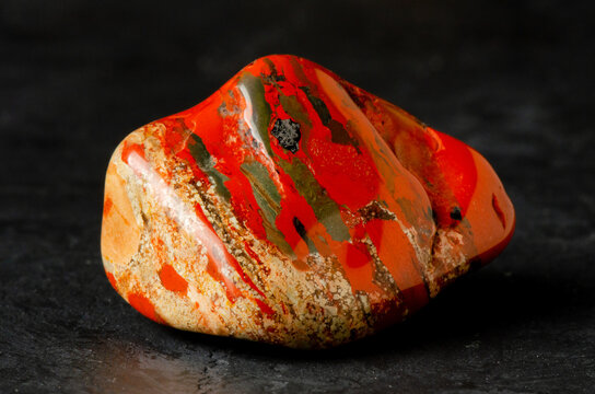 Stone mineral jasper on a black concrete background. The concept of using minerals and crystals in astrology and alternative or complementary medicine.