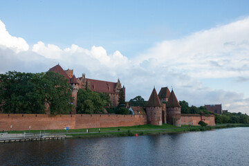 Obraz premium Beautiful view of Malbork castle next to the river. Fort and buildings.
