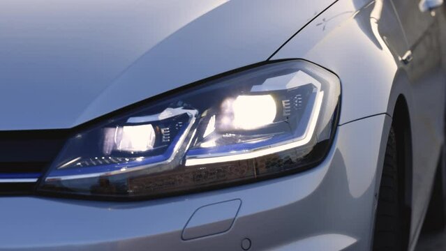 Close up of modern car headlamp. Switched on led lights of luxury car. Car flashing light with blinking indicator. Car Blinker Light, car light blinking on continuously. Car Front Full Led Light