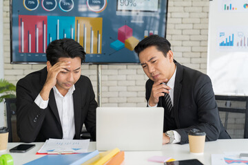 Group of Asian businessmen working with headache in the office. Stressful Asian businessman working with laptop and touching his forehead. Office syndrome concept.