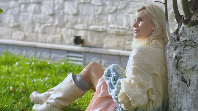 Portrait of a charming woman sitting under a tree in the garden