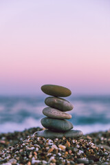 Obraz na płótnie Canvas Pyramid of pebbles on the beach at sunset. Concept of zen, stability, harmony, balance and meditation, copy space.