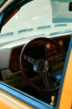 Vertical Shot Of A Vintage Yellow Car With A Rolled Down Window Showing A Stylish Steering Wheel