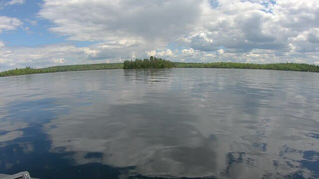 POV from fishing boat while rapidly cruising over open waters of Lake Vermilion in northern Minnesota; passing by island and shore; concepts of fishing, boating, and vacation