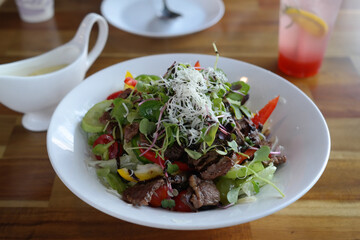 Salad is served on a white round plate.