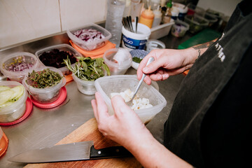 cook's hands preparing food in a container on a restaurant kitchen bar