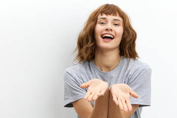a happy, sweet, joyful woman with red hair and a beautiful hairstyle looks smiling at the camera, holding out her hands in front of her