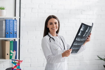 Smiling doctor holding mri scan and looking at camera in clinic