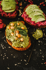 Beetroot hummus and avocado on a toast of dark bread. Tasty sandwich of vegan recipes. Homemade healthy organic food. Vegetarian cuisine. Top view 