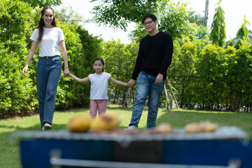 Family holiday activities include father, mother and children with camping barbecue and play in the yard together happily on vacation.