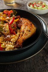Braised chicken leg with spiral noodles and roasted vegetables.
