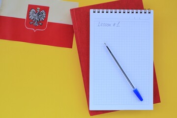 Flag of Poland, notebook and textbook on yellow background. Travel and learning speaking foreign...