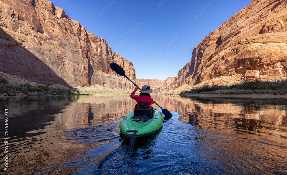 Wall mural adventurous woman on a kayak paddling in colorado river. glen canyon, arizona, united states of amer