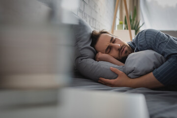 Young man sleeping on bed at home in morning