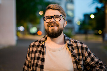 Portrait of man standing in night city street with bokeh street lights in background. Confident...