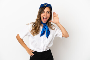 Airplane stewardess over isolated white background listening to something by putting hand on the ear