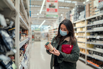 mature latin woman with mask choosing or  looking at groceries in supermarket